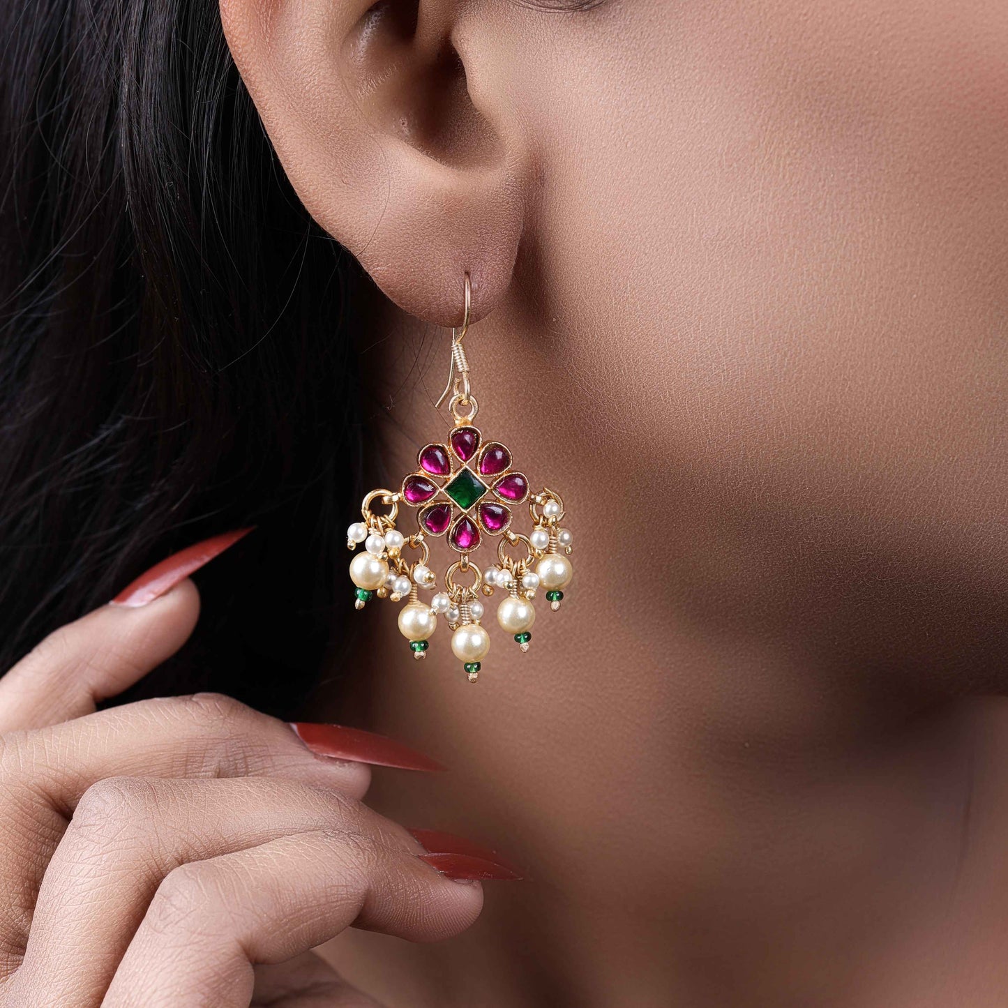 Gold-plated floral chandelier earrings with red and green gemstones, pearl drop accents, and intricate detailing, perfect for ethnic and festive wear.