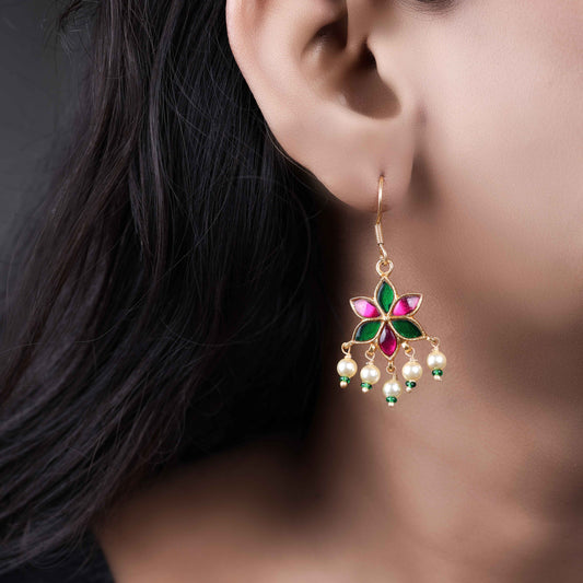 A gold-plated floral drop earring with pink and green enamel petals, featuring dangling freshwater pearls and green bead accents, worn by a model.
