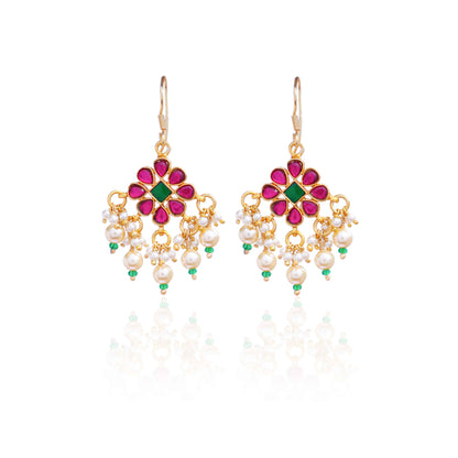 Gold-plated floral chandelier earrings with red and green gemstones, pearl drop accents, and intricate detailing, perfect for ethnic and festive wear.