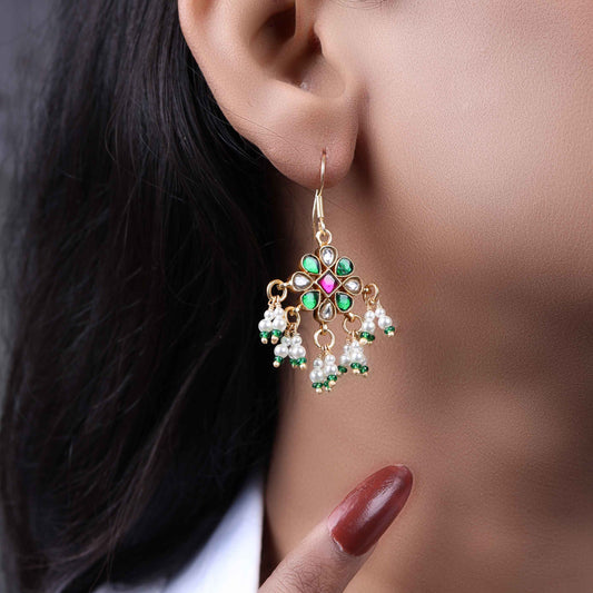 Gold-plated Kundan earrings with a floral motif, pink, green, and white gemstones, and dangling pearl clusters, worn by a model.