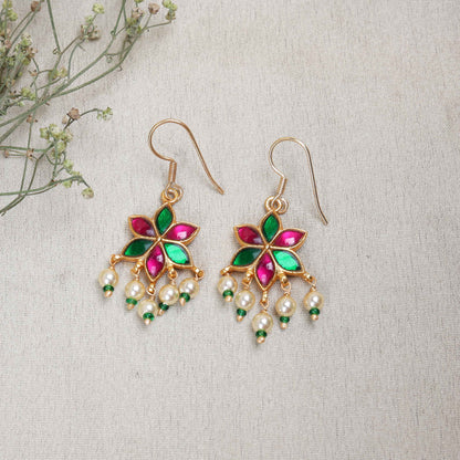 A gold-plated floral drop earring with pink and green enamel petals, featuring dangling freshwater pearls and green bead accents, worn by a model.