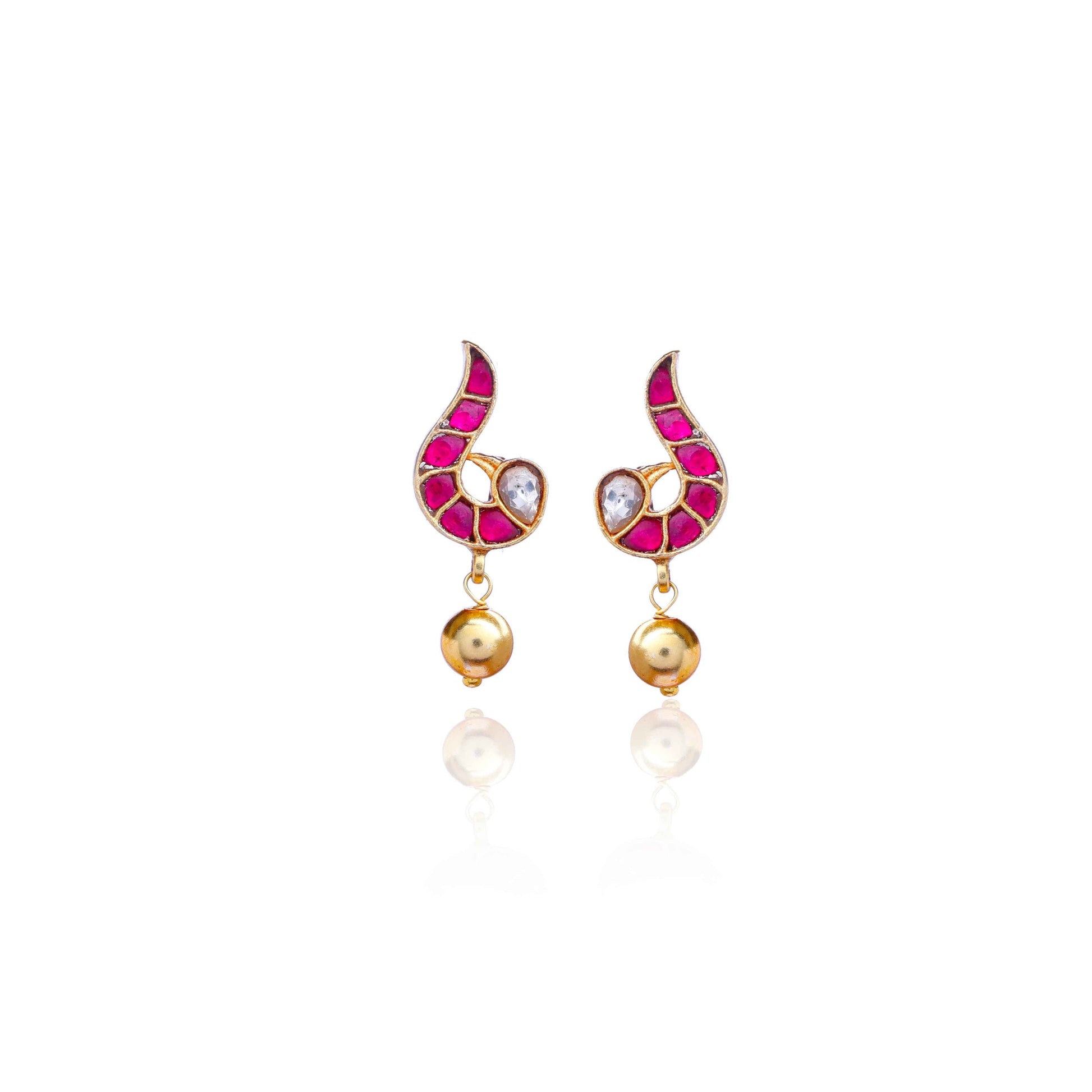 A close-up image of a woman's ear wearing a gold-toned paisley-shaped stud earring with ruby-red stones, a white gemstone accent, and a dangling gold bead.