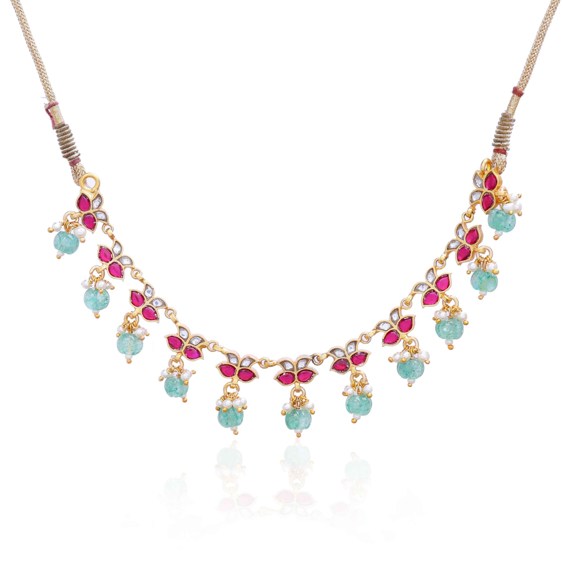 Gold-plated Kundan choker necklace with ruby-red, white stones, and dangling emerald-green beads, displayed on a neutral background.