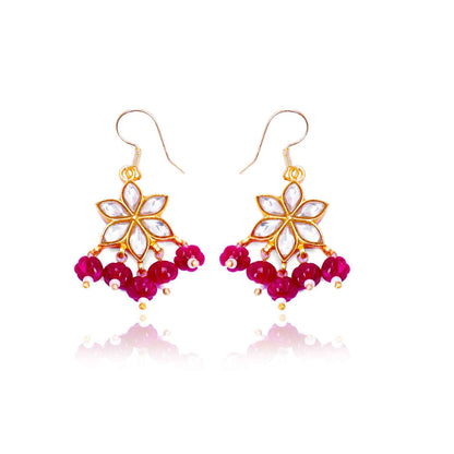 Gold-plated floral Kundan earrings featuring a six-petal design with clear gemstones and dangling red beads, elegantly worn by a model.