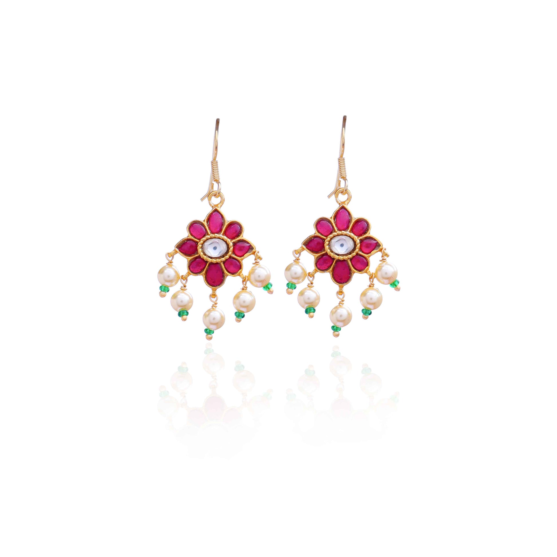 Gold-plated floral Kundan earrings with a central clear gemstone, surrounded by ruby-red stones and dangling pearl beads, worn by a model.